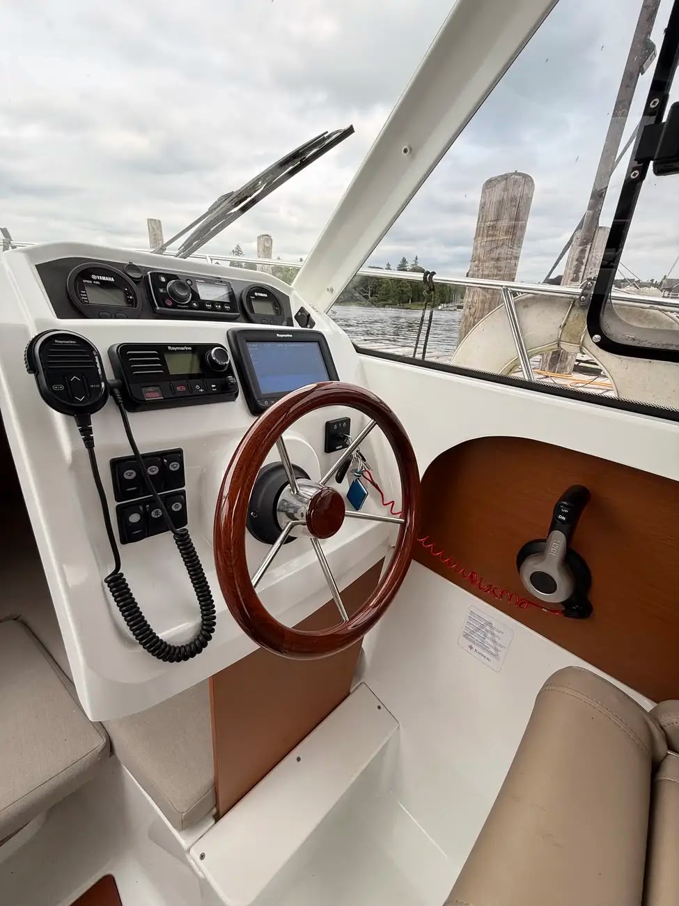 Close-up of the wooden wheel and Raymarine chartplotter and VHF at the helm