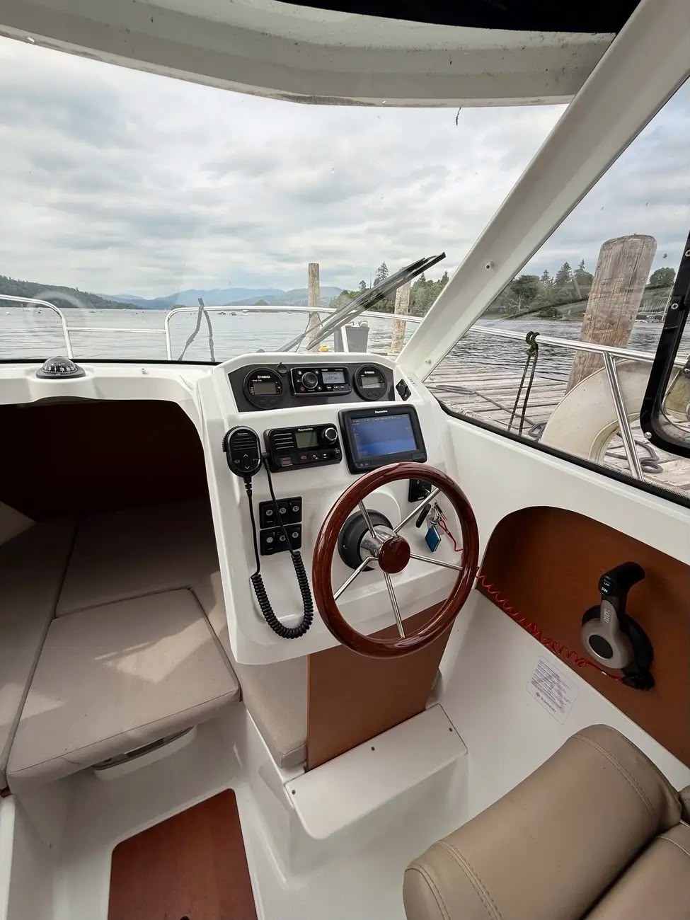 The helm of the Merry Fisher 605 with wooden wheel, Raymarine electronics and lake view