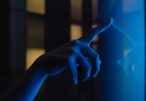 Hand touching a glowing digital interface in blue light