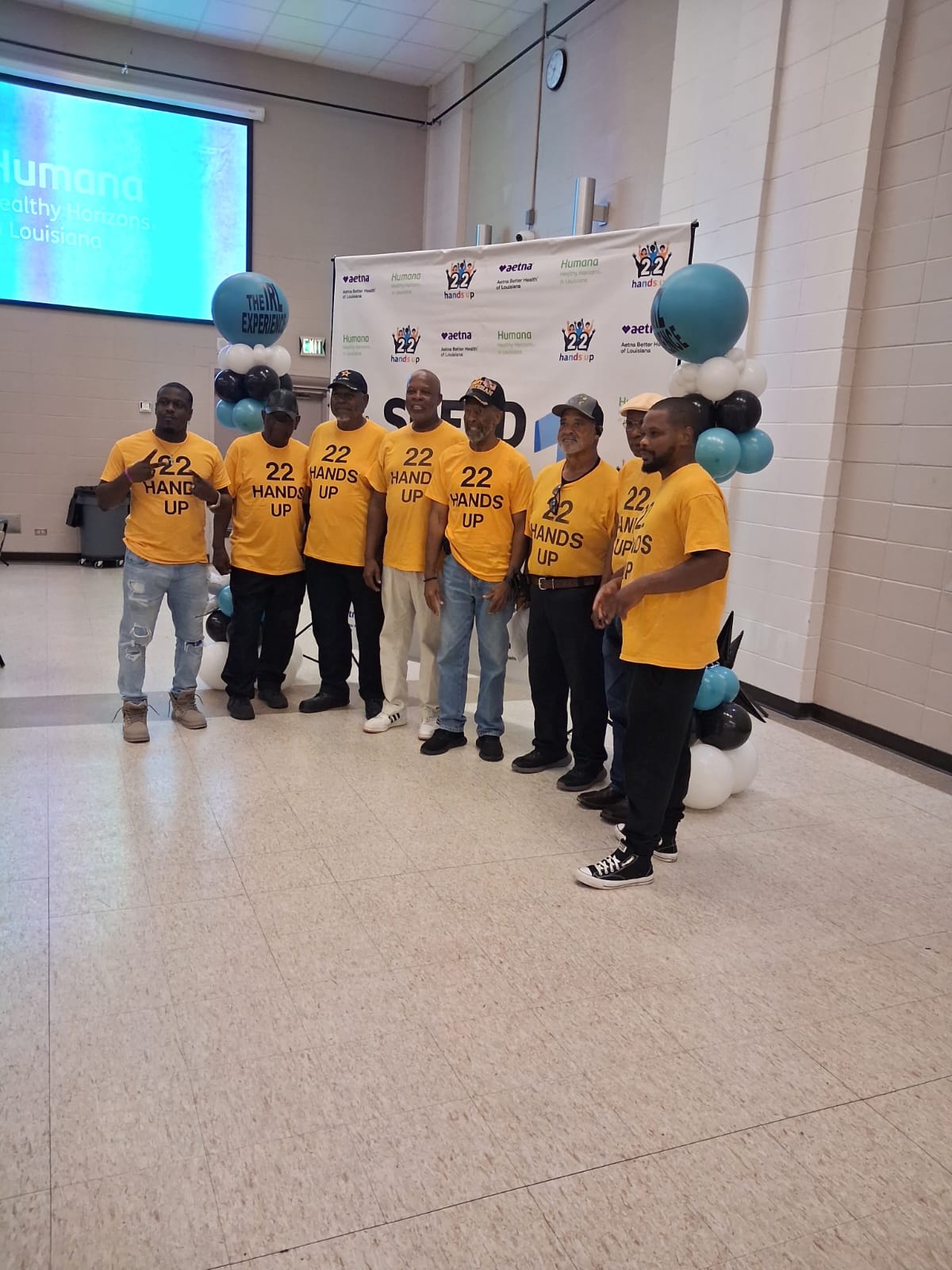Group of volunteers in yellow 22 Hands Up shirts posing together at the event