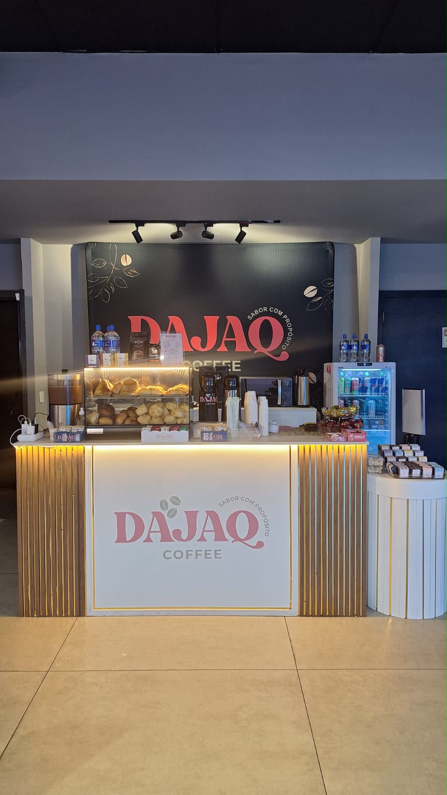 Balcão DAJAQ COFFEE com acabamento dourado e painel de marca em evento corporativo