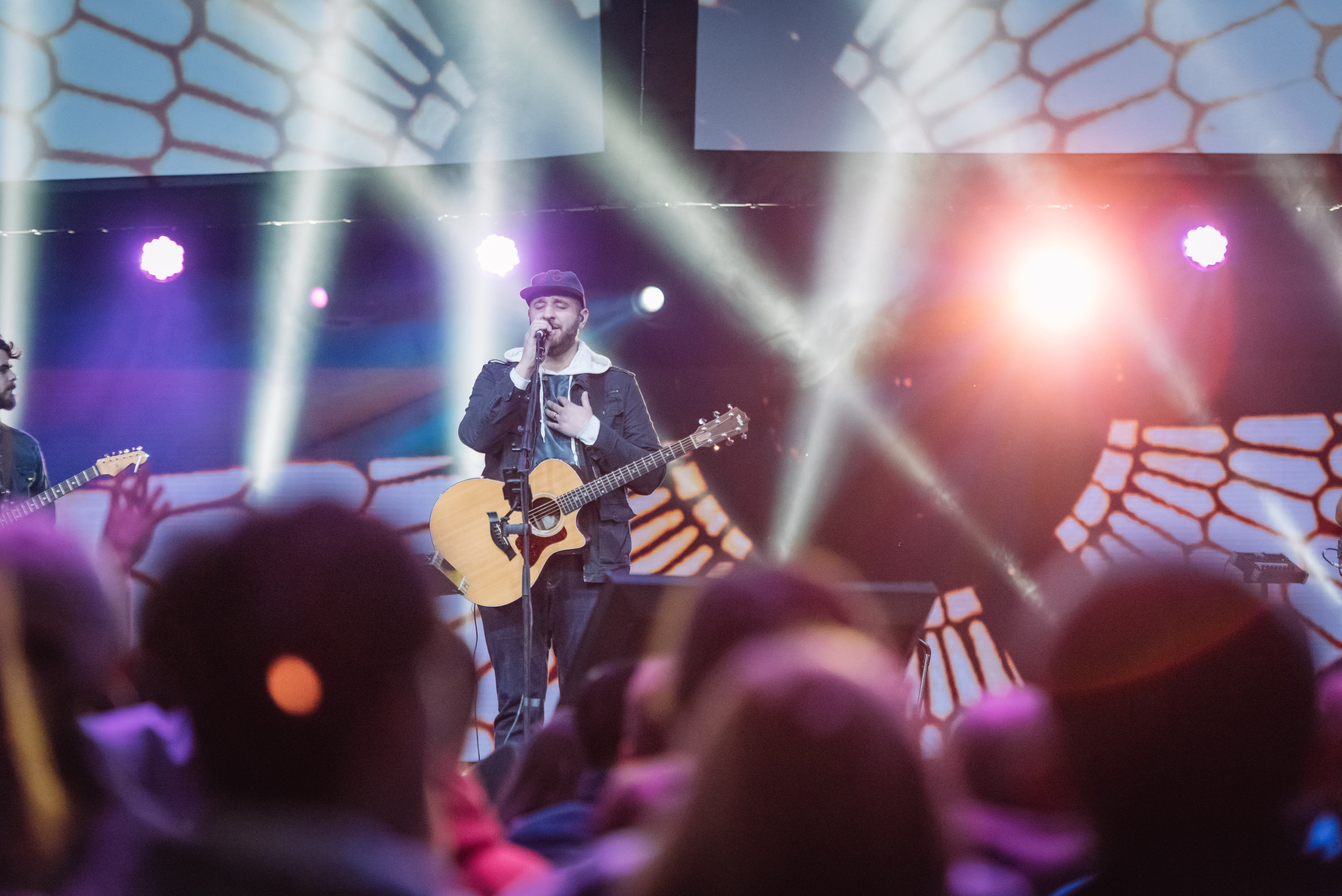 Justin Rizzo leading worship on stage with an acoustic guitar