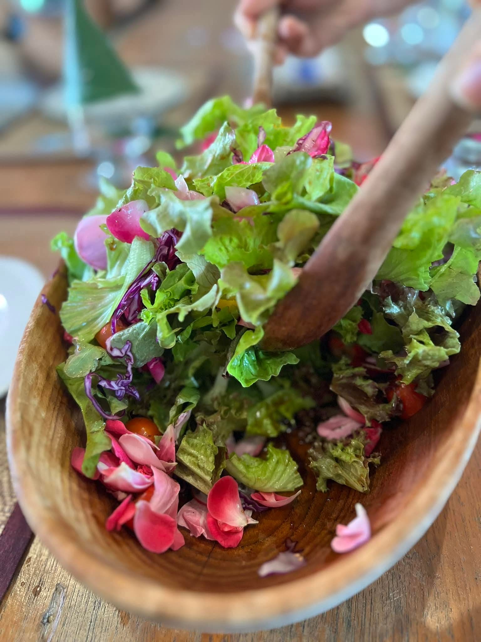 Fresh garden salad with rose petals in wooden bowl