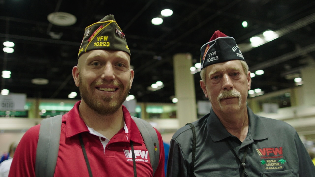 Two generations of VFW members at a national convention, both wearing VFW Post 10223 caps