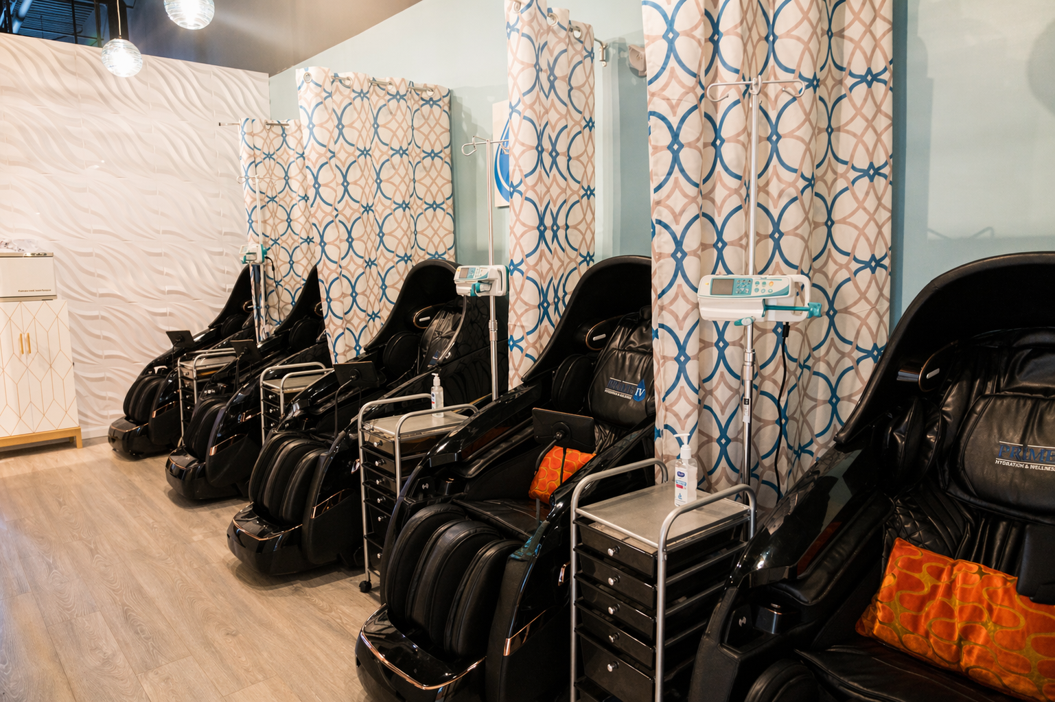 A row of branded black zero-gravity recliners with patterned privacy curtains in the VIP lounge