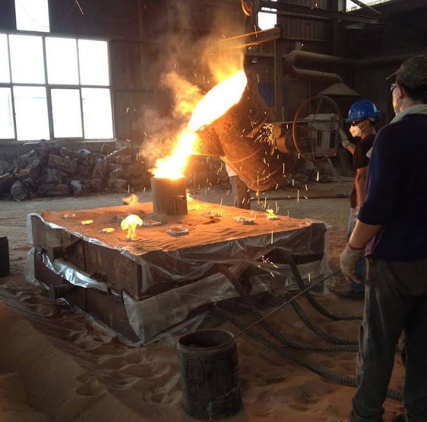 Workers pouring molten metal into molds
