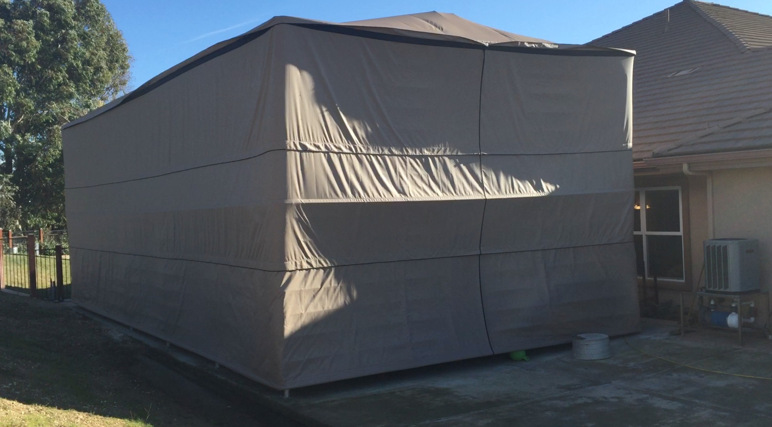 Freestanding automatic canopy cover closed over a vehicle on land