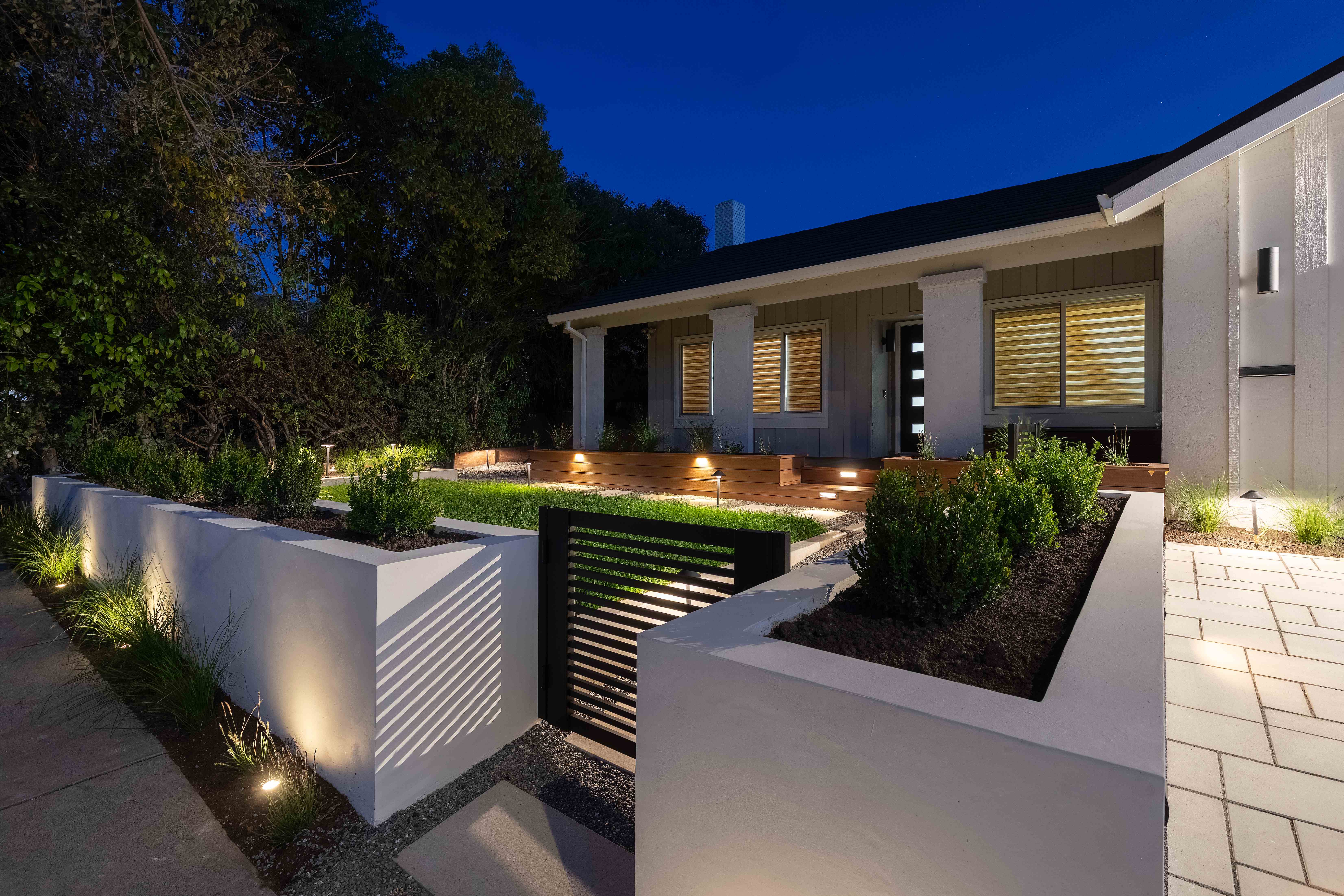 Front yard transformation in Fremont featuring modern landscaping with concrete pavers and raised planters at twilight