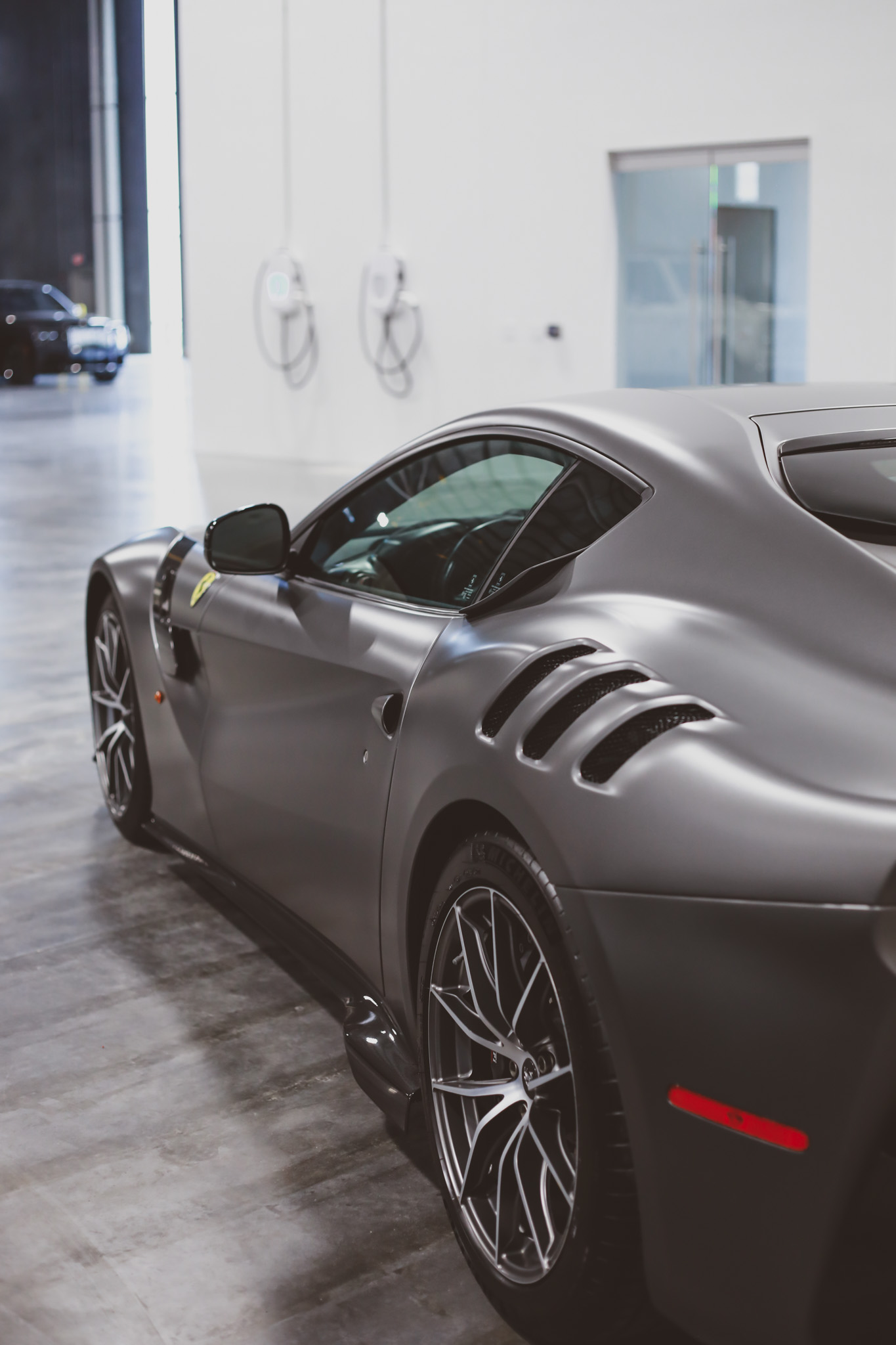 Ferrari F12 Berlinetta in matte graphite rear 3/4 with side intakes, white studio