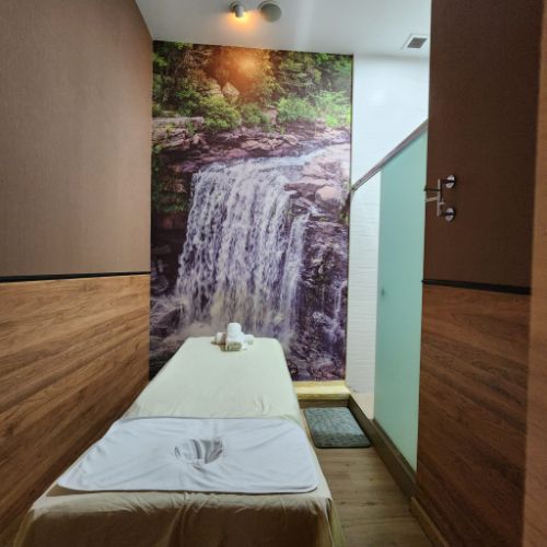 Private massage room with waterfall mural and treatment bed