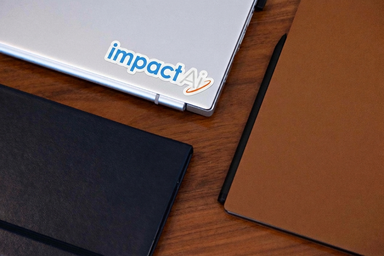 Impact AI branded laptop with notebooks and stylus on a desk