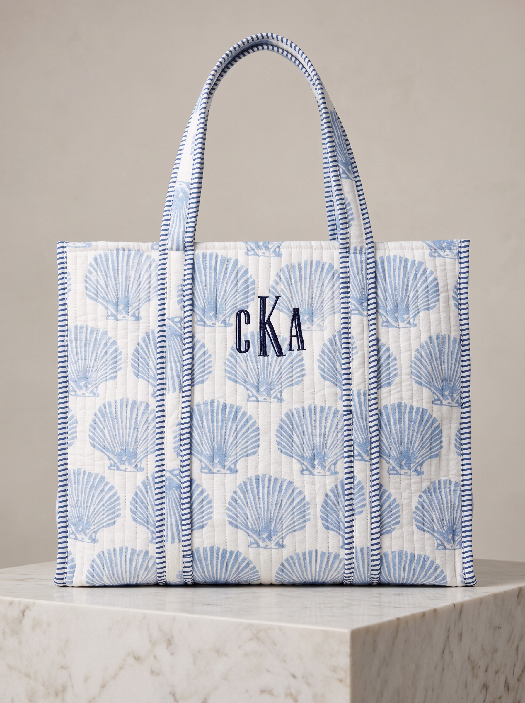 Made from cotton with a soft shell print, pale blue quilting, and navy striped trim.