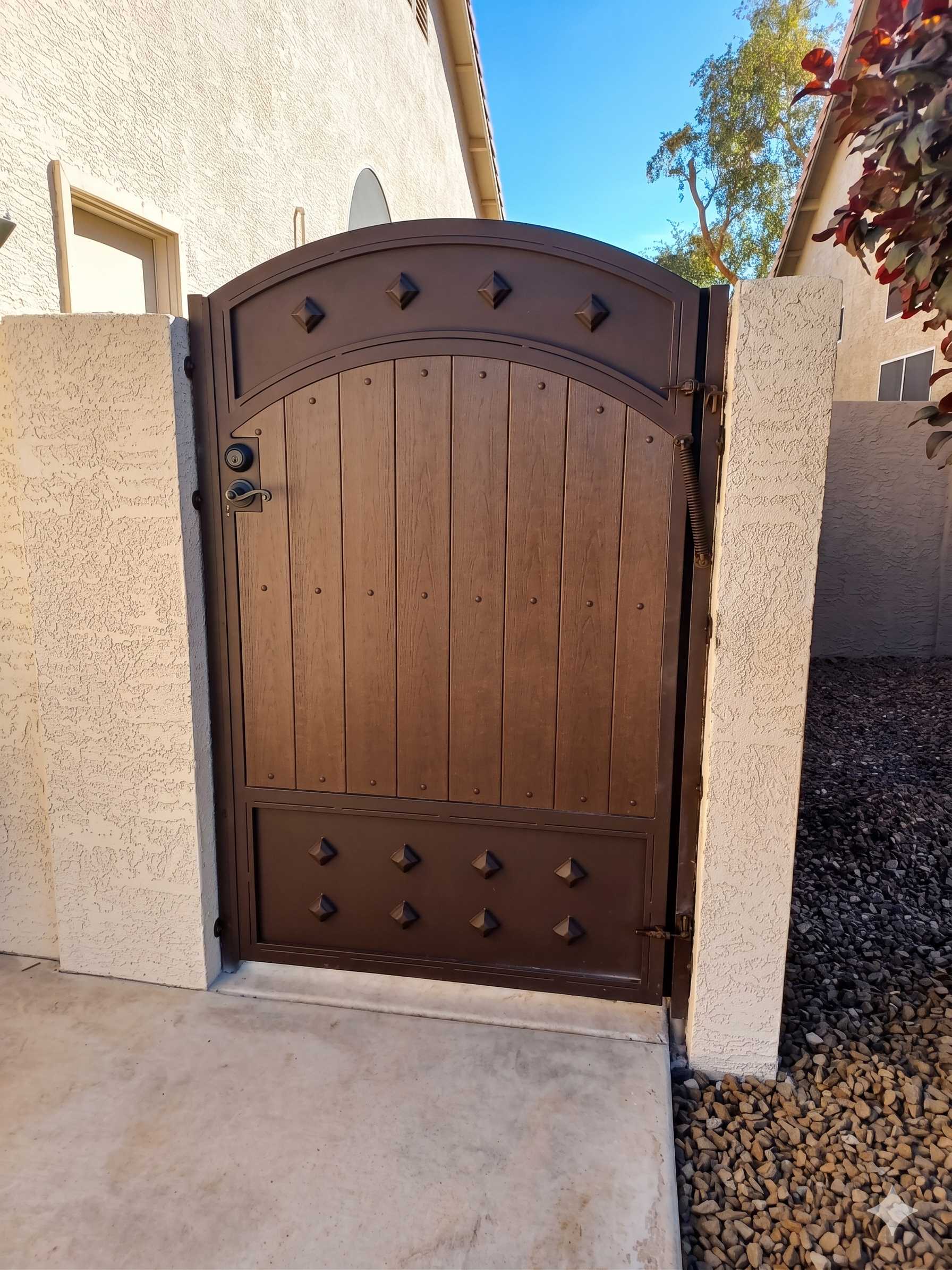Arched side gate with wood grain panels and diamond accents in bronze finish