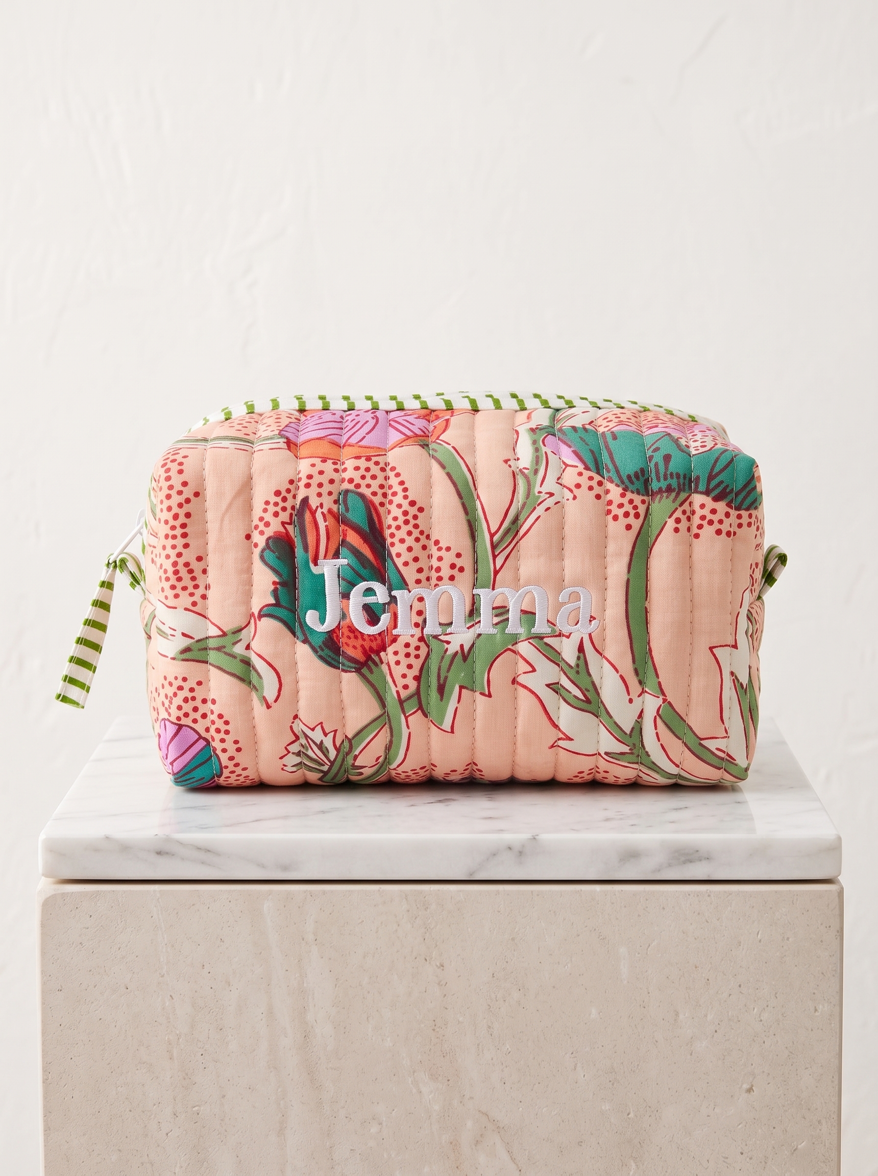 Made from cotton, this cheerful peach-toned pouch features a colorful garden print.