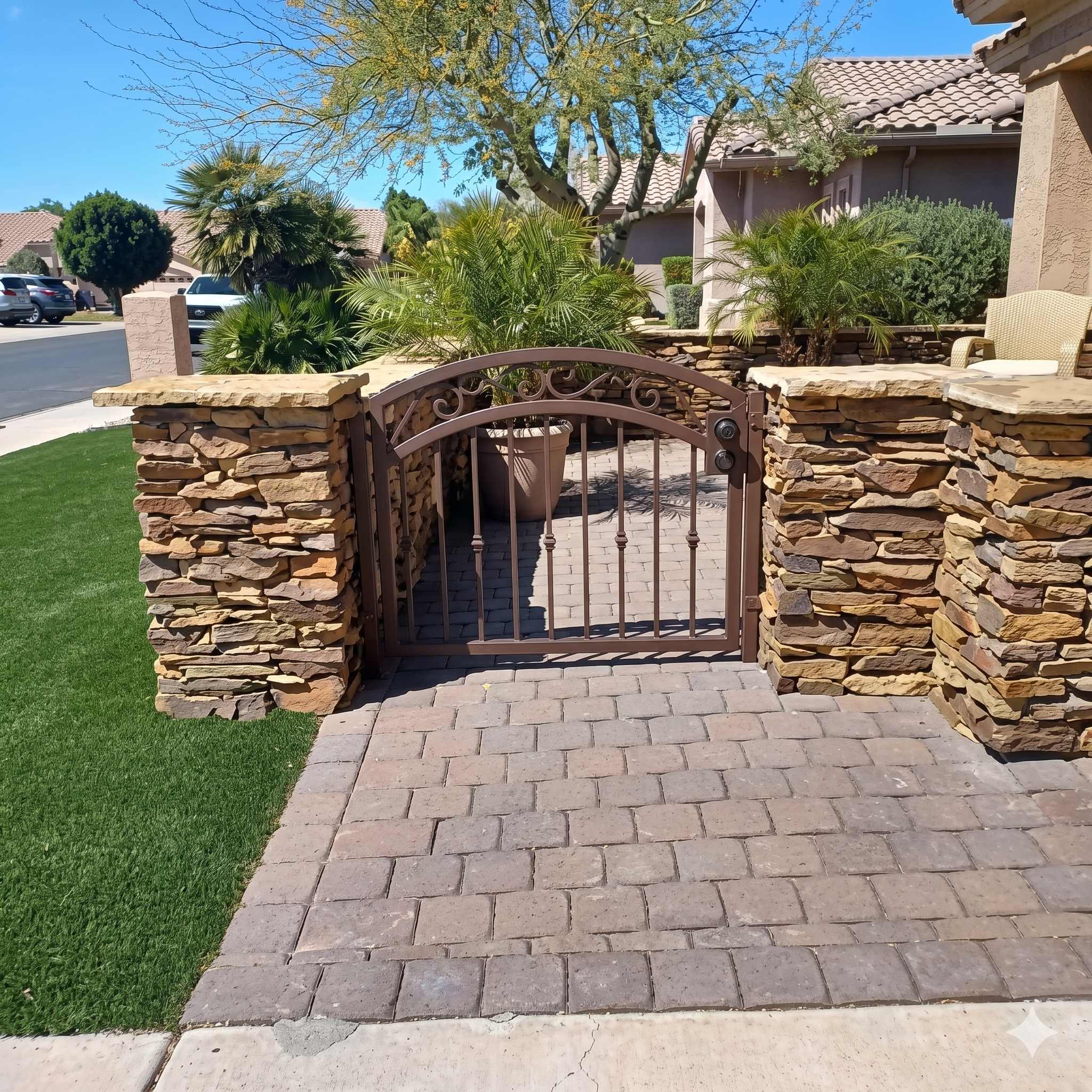 Courtyard entry gate with bronze scrollwork between stone pillars