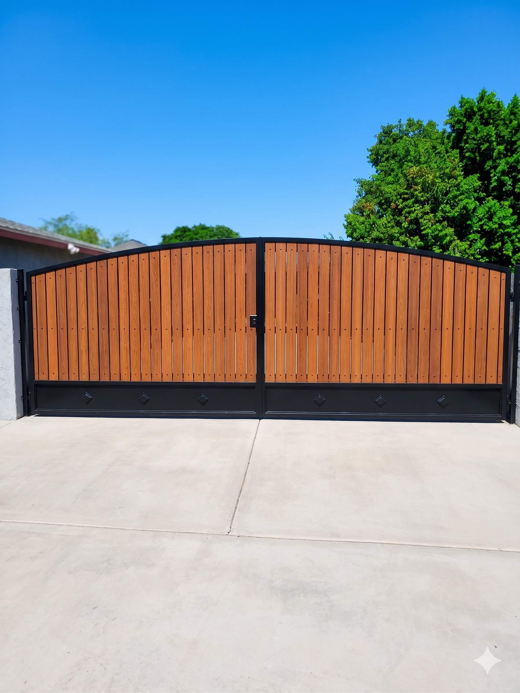 Large arched double RV gate with orange wood panels and black frame with diamond accents