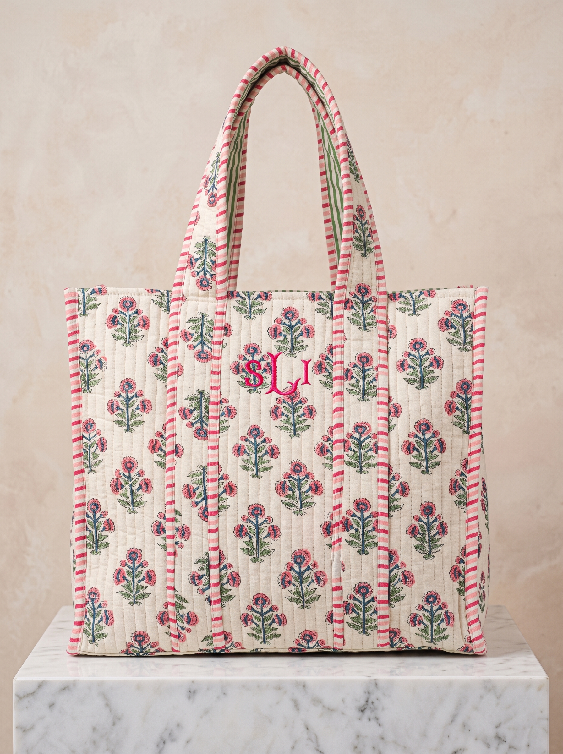 Made from cotton, this cream tote is patterned with pink blooms and finished with striped handles.