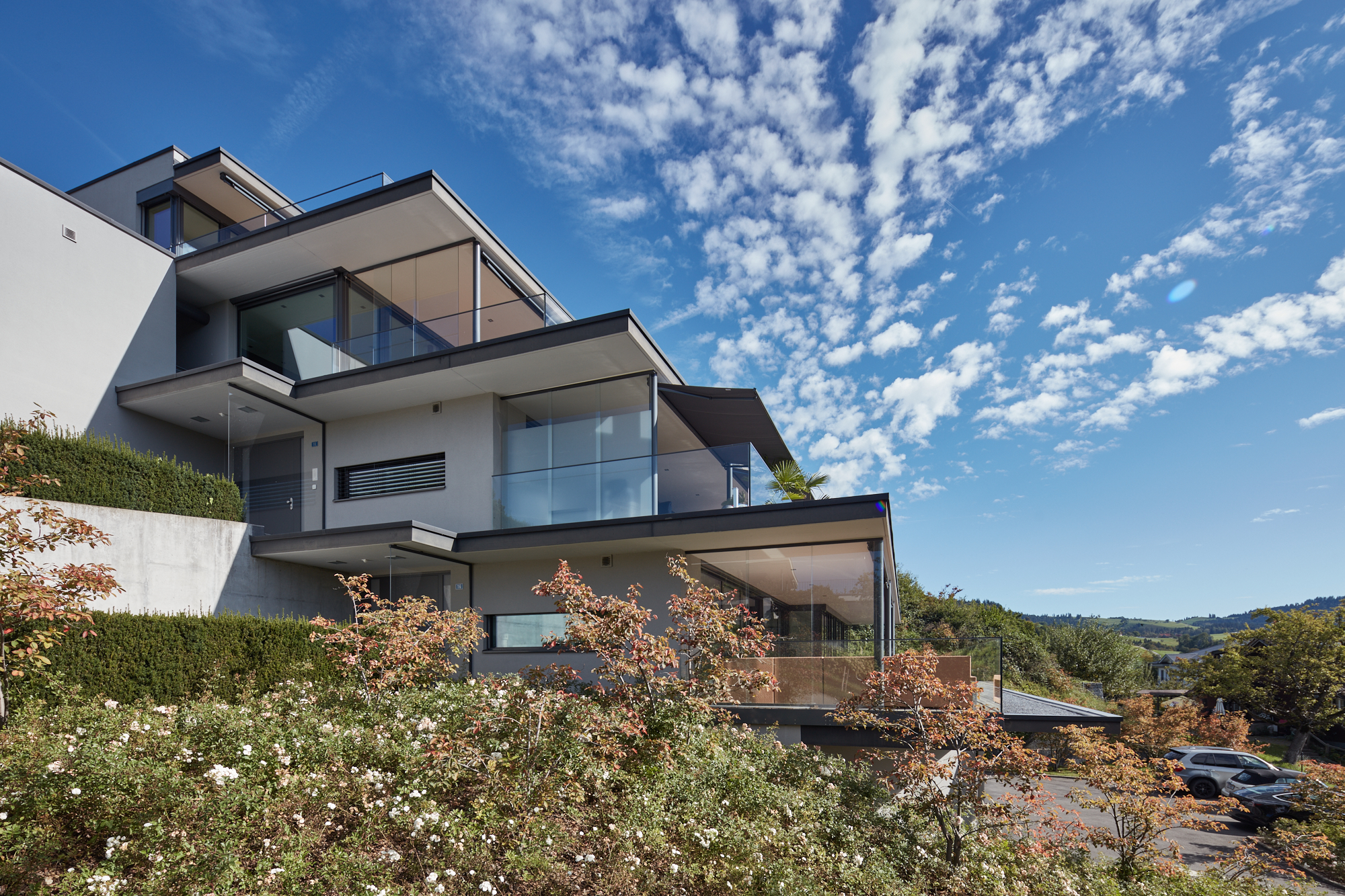 Modernes Terrassenhaus mit Glasgeländern und Gartenanlage