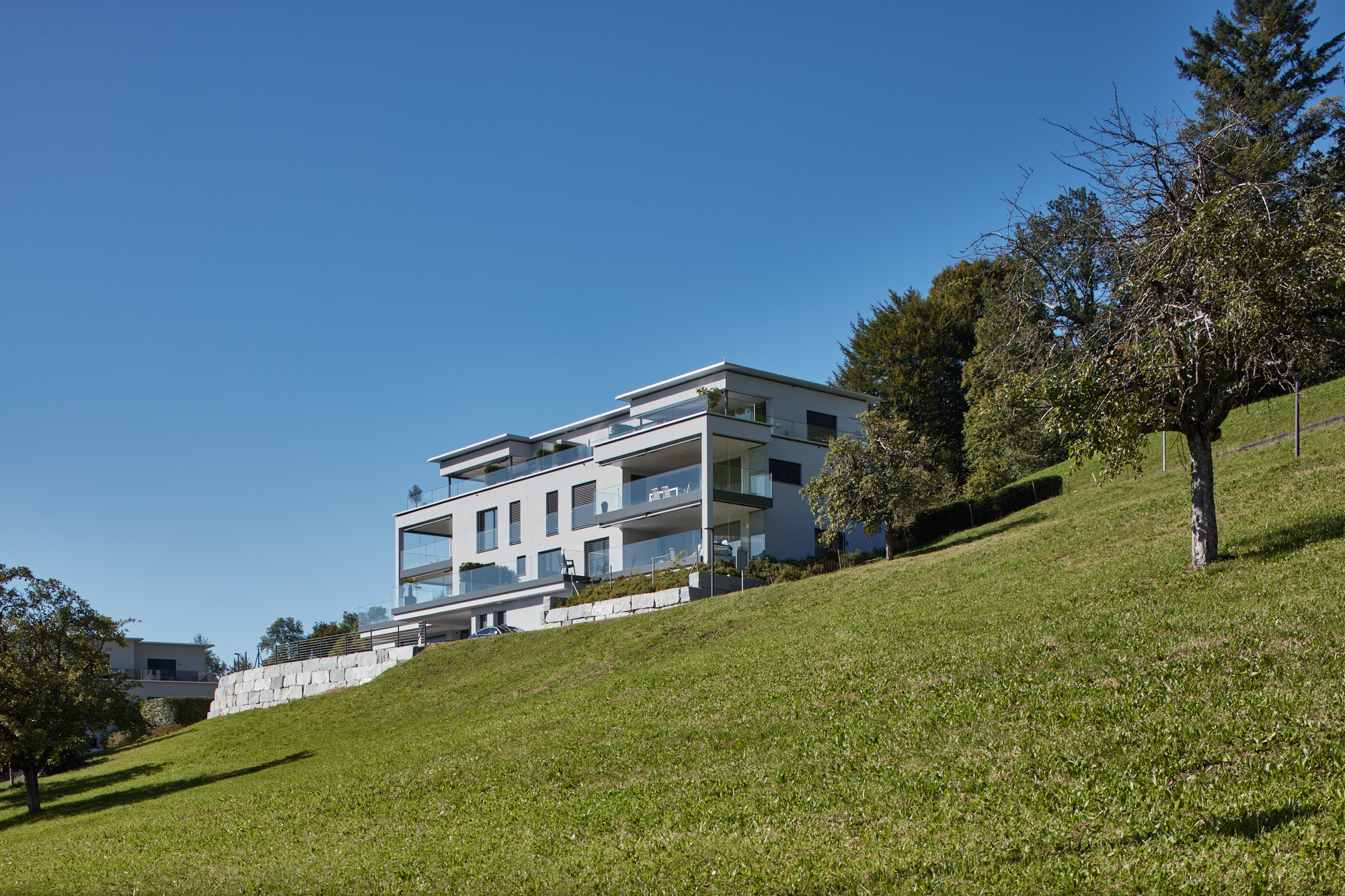 Terrassenhaus mit Glasbalkonen und Natursteinmauer