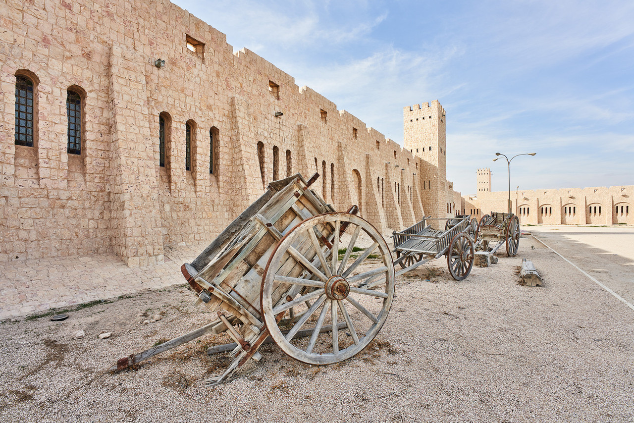 Historical fort in Qatar with traditional wooden carts showing the country's rich heritage