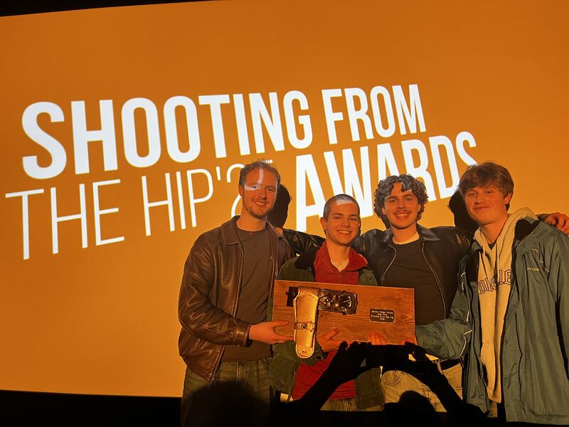 The Hush team holding their award beneath a Shooting From the Hip projection