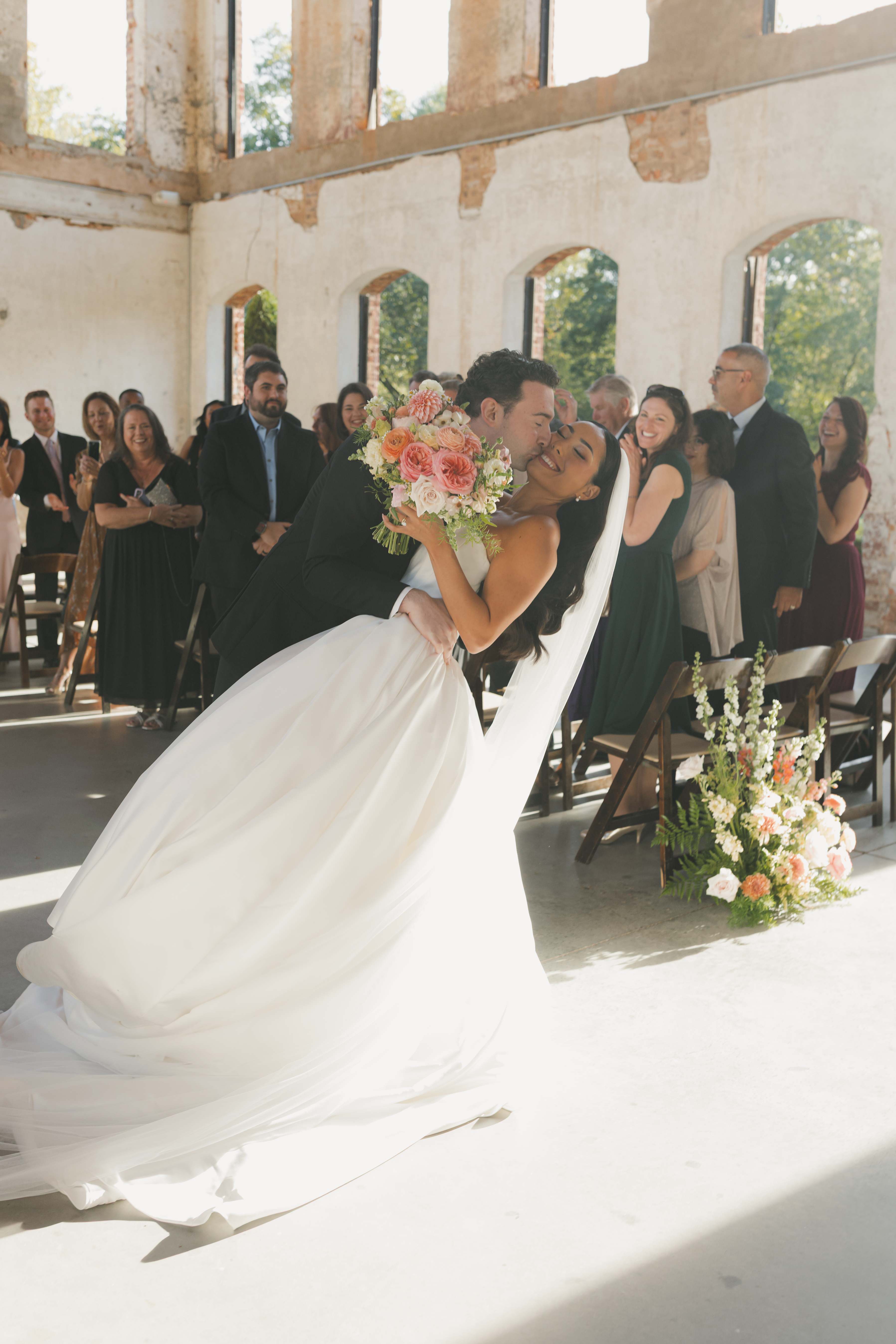 Bride and groom kissing during their recessional as guests applaud