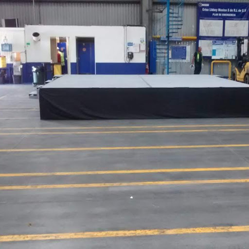 Tarima blanca elevada en espacios industriales con piso marcado en amarillo, estructura de hangar profesional