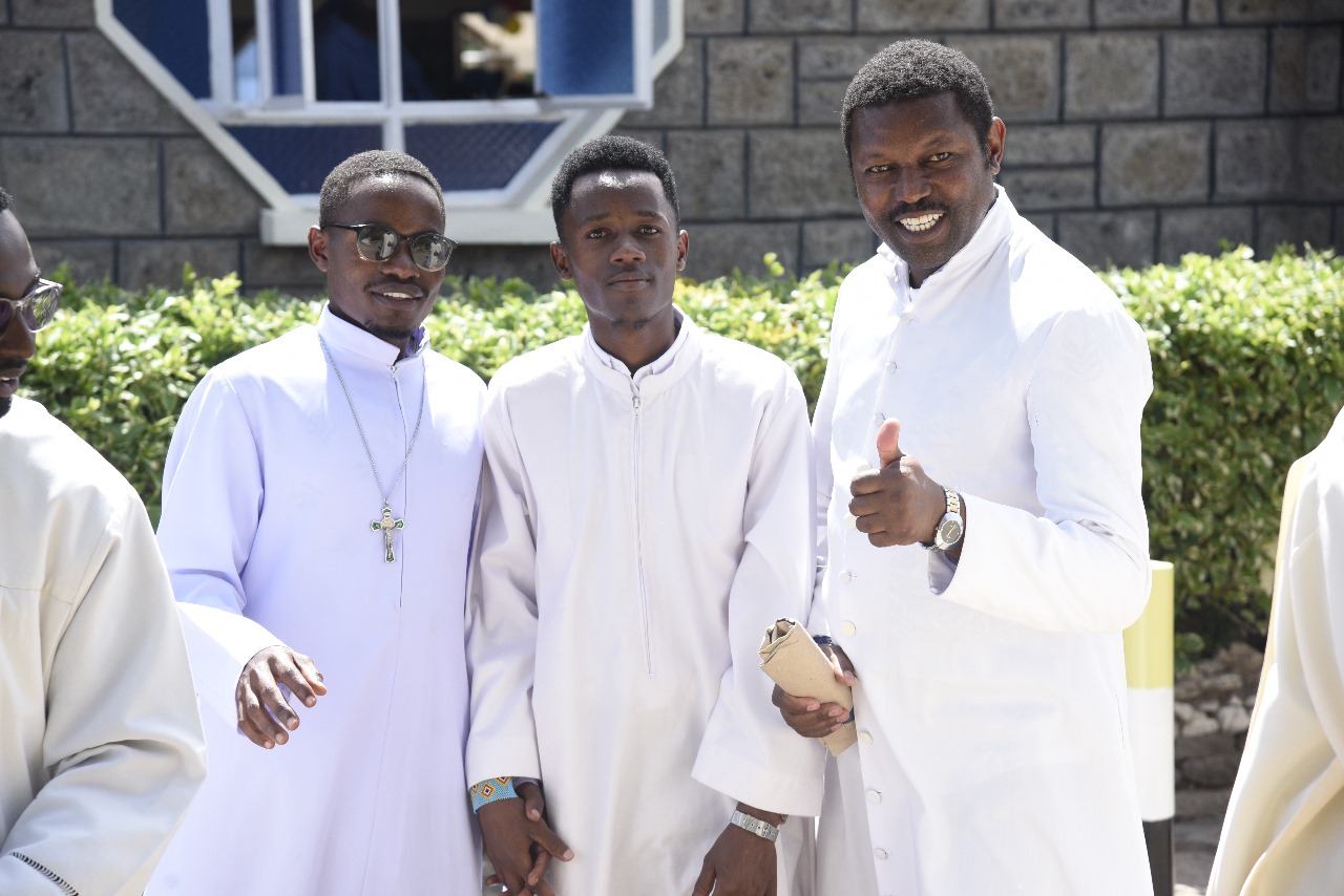 clergy members in white vestments sharing a moment of fellowship