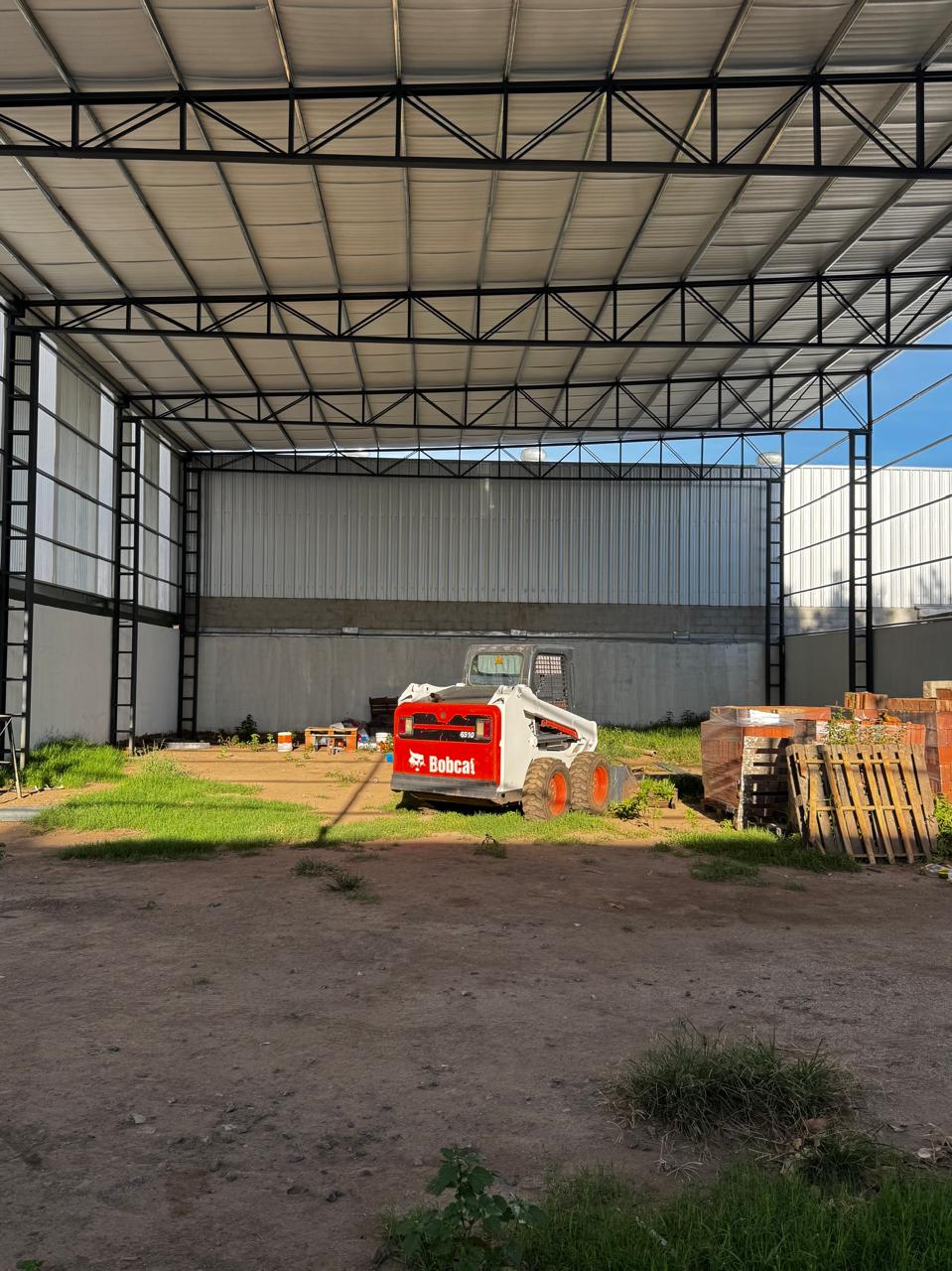 Vista posterior de minicargadora Bobcat bajo techo metálico