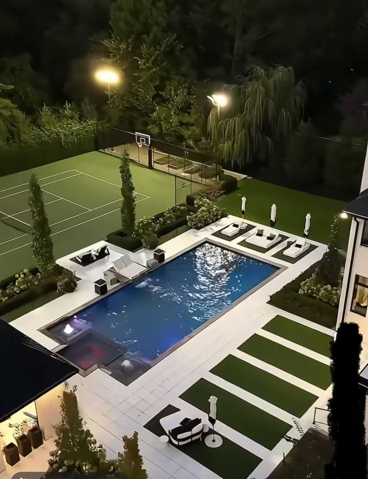 Night view of backyard with pool, tennis court and outdoor seating