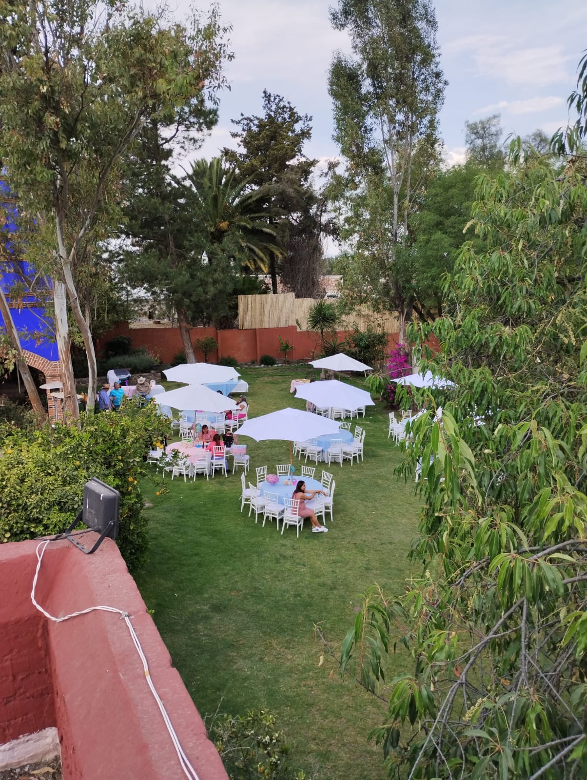 Vista aérea del jardín con mesas y sombrillas listas para una celebración
