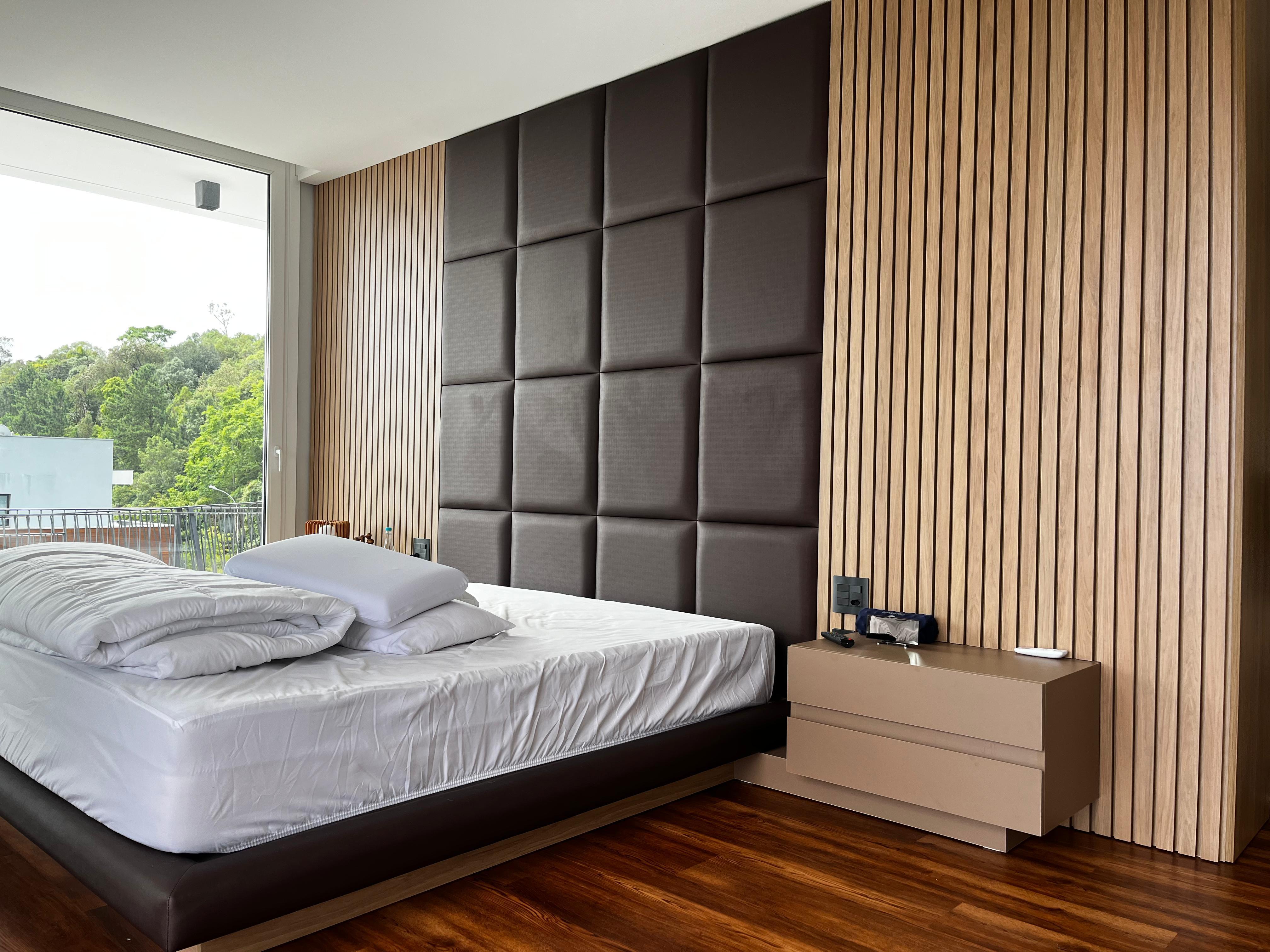 Quarto principal com painéis acolchoados e parede de ripas de madeira