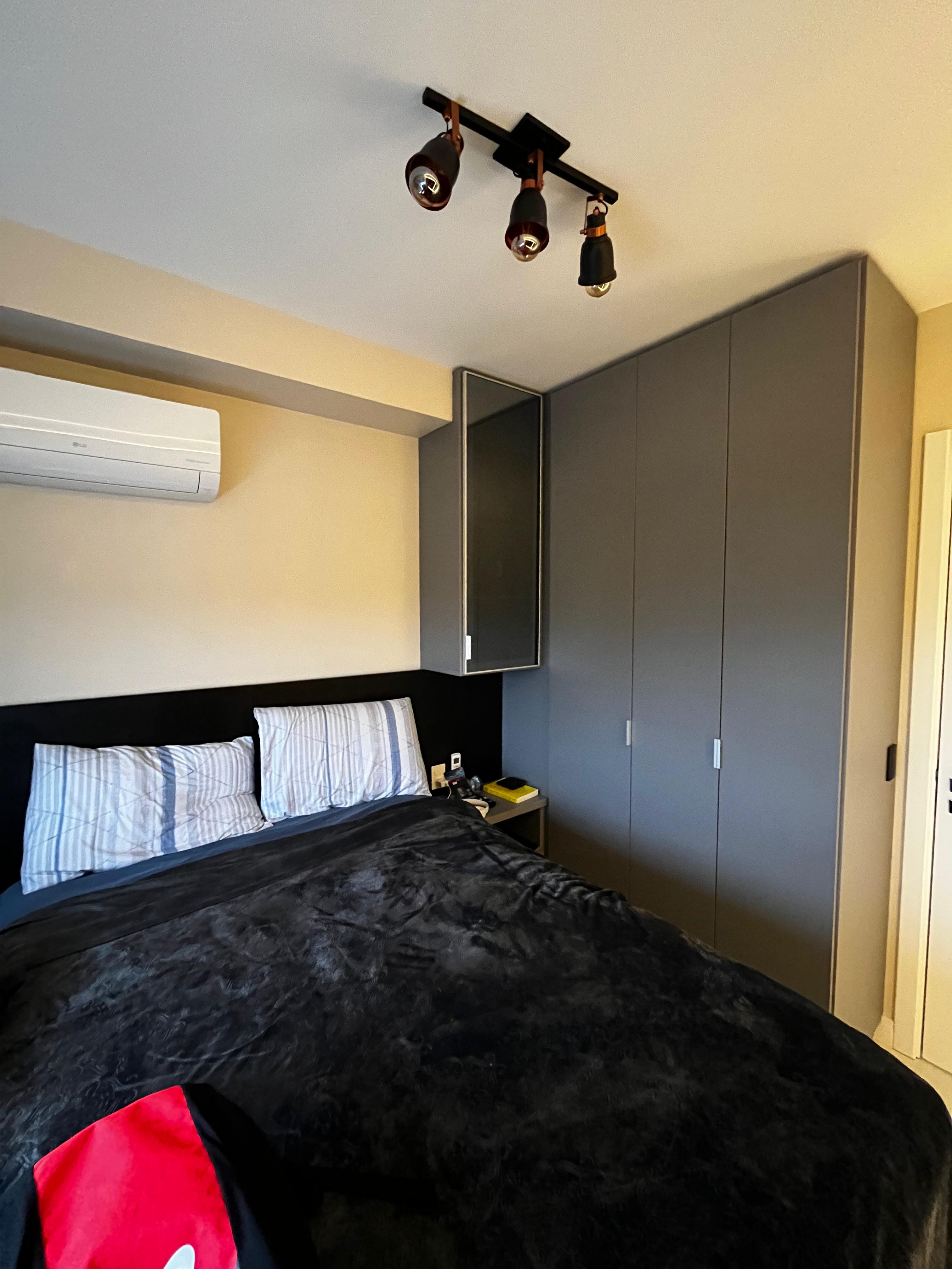Quarto com cabeceira preta e guarda-roupa espelhado
