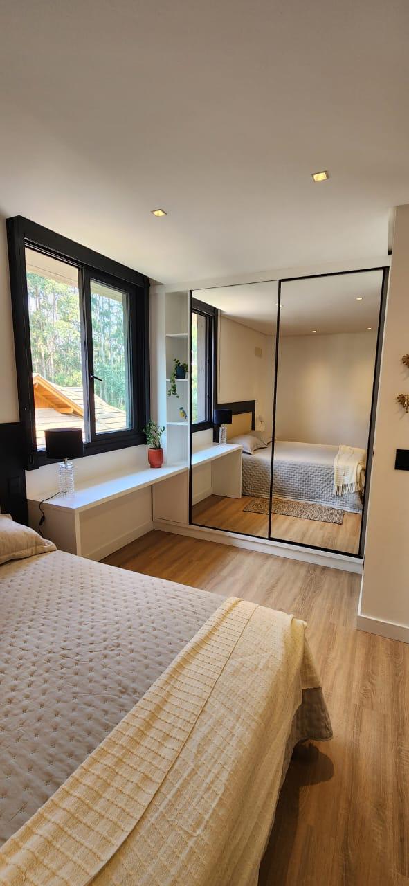 Quarto moderno com guarda-roupa espelhado e bancada suspensa