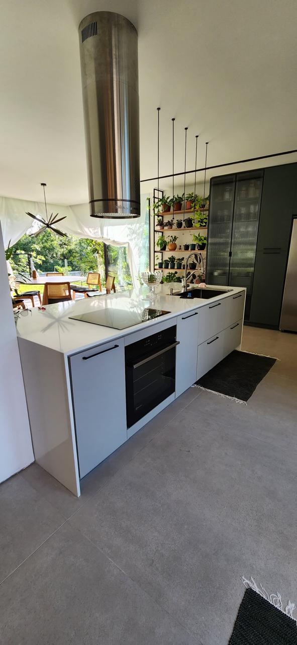Cozinha contemporânea com ilha branca e coifa cilíndrica