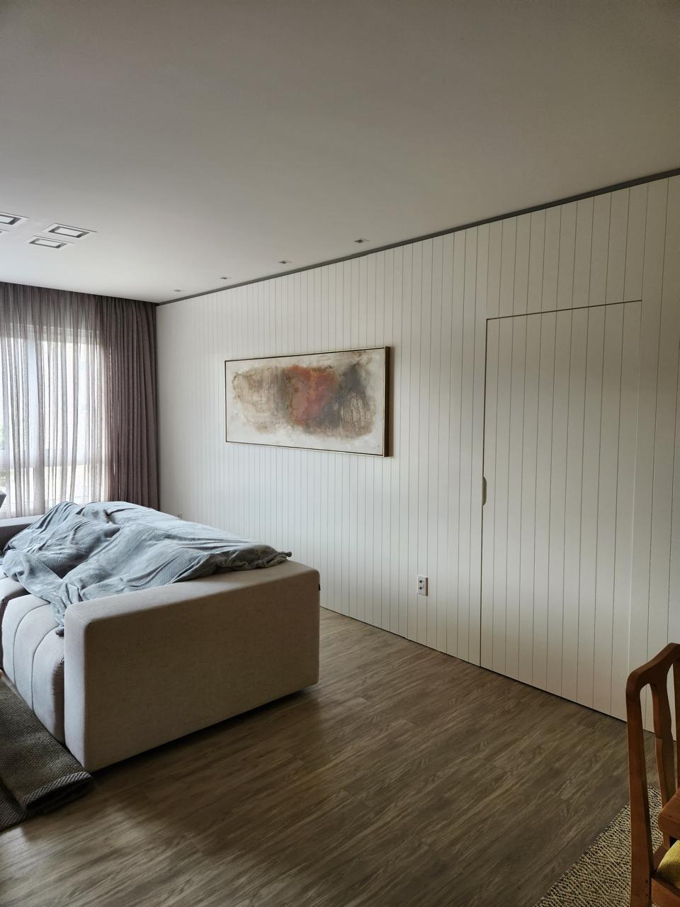 Sala minimalista com painéis de madeira vertical e obra de arte