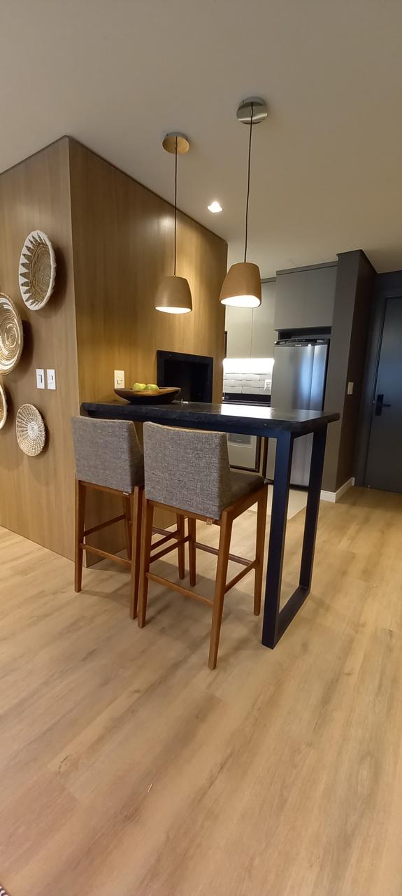 Espaço gourmet com mesa alta preta e decoração em madeira