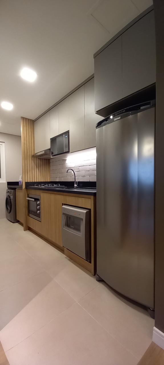 Cozinha compacta com armários cinza e madeira, eletrodomésticos integrados