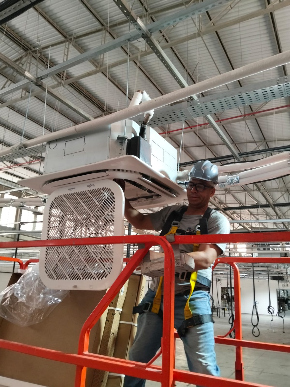 Profissional em plataforma elevada trabalhando em unidade de ar