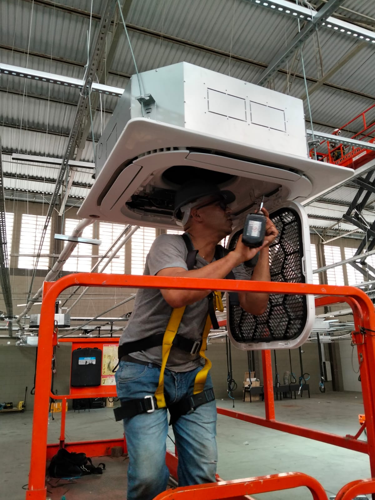Técnico em plataforma elevada instalando unidade de ar condicionado