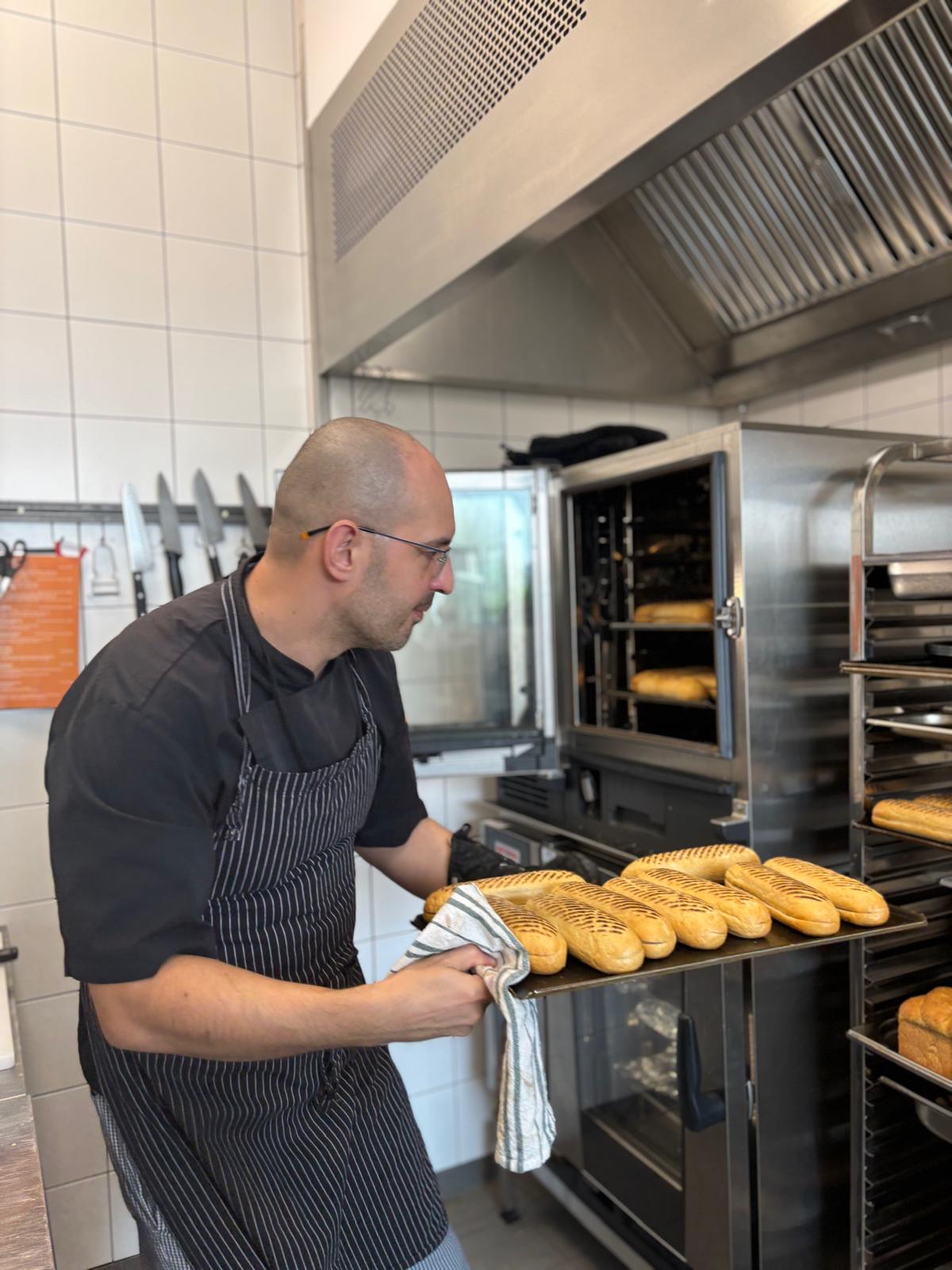 Marcin Koniuszko taking bread out of the oven