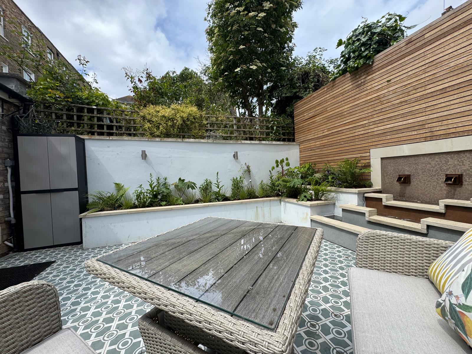 Contemporary courtyard with patterned encaustic floor tiles and a tiled water feature