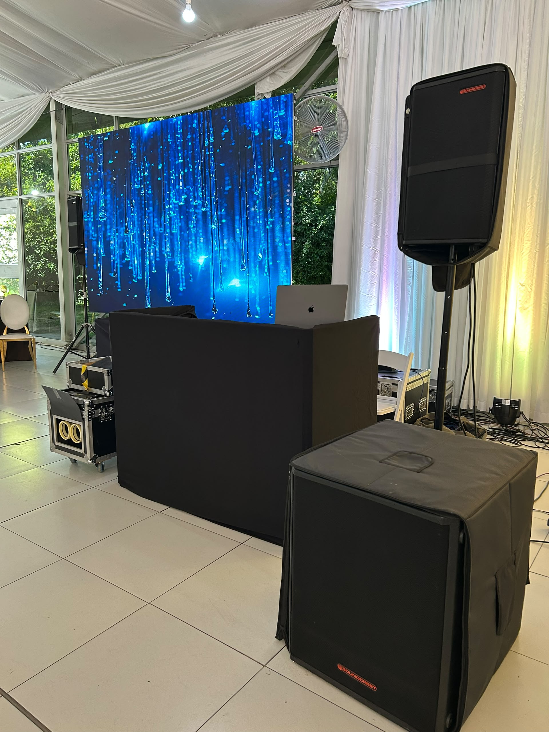 Outdoor wedding event tent with blue LED video screen display and black DJ booth