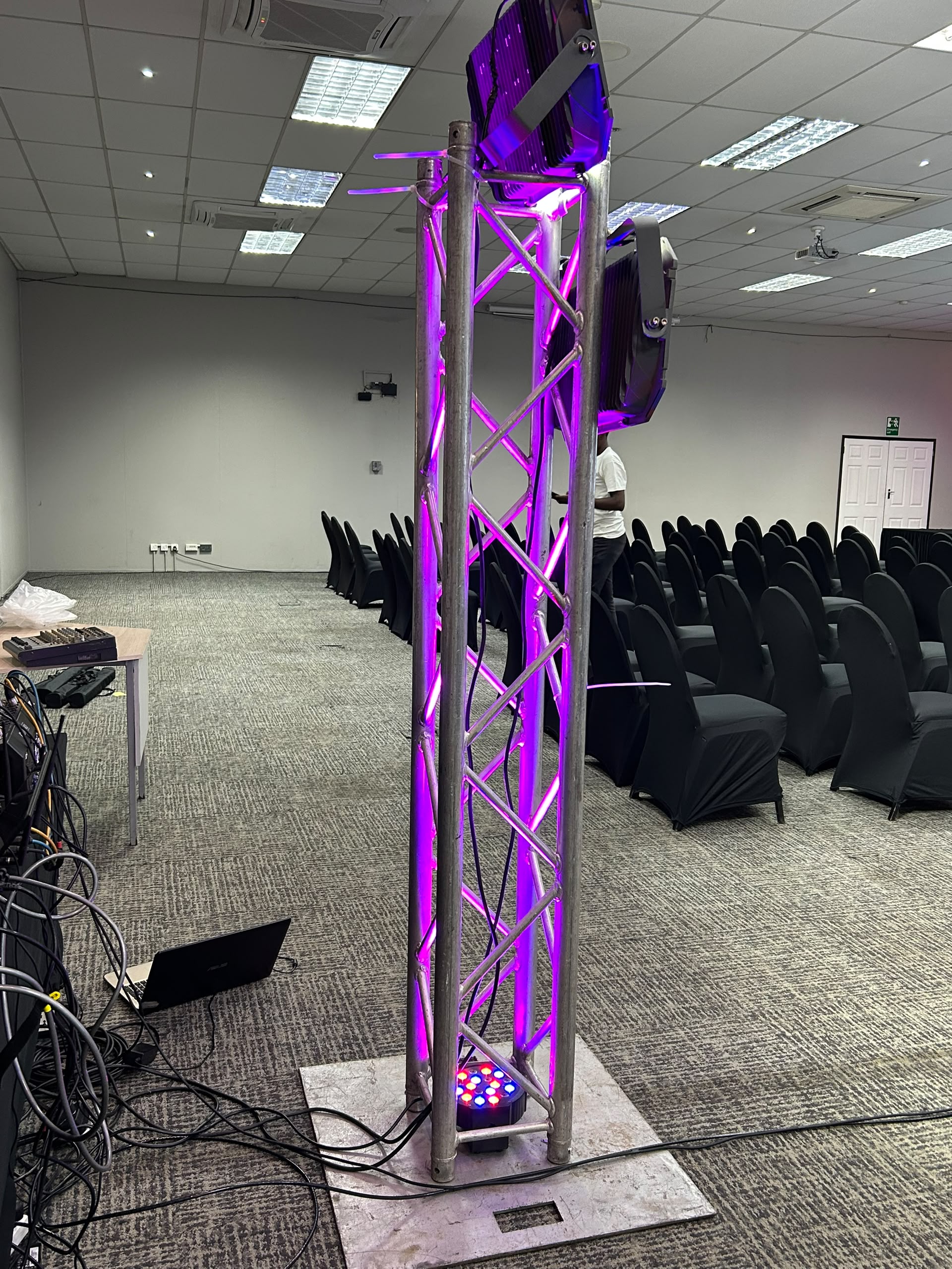 Professional stage setup with purple LED-lit metal truss and black seating