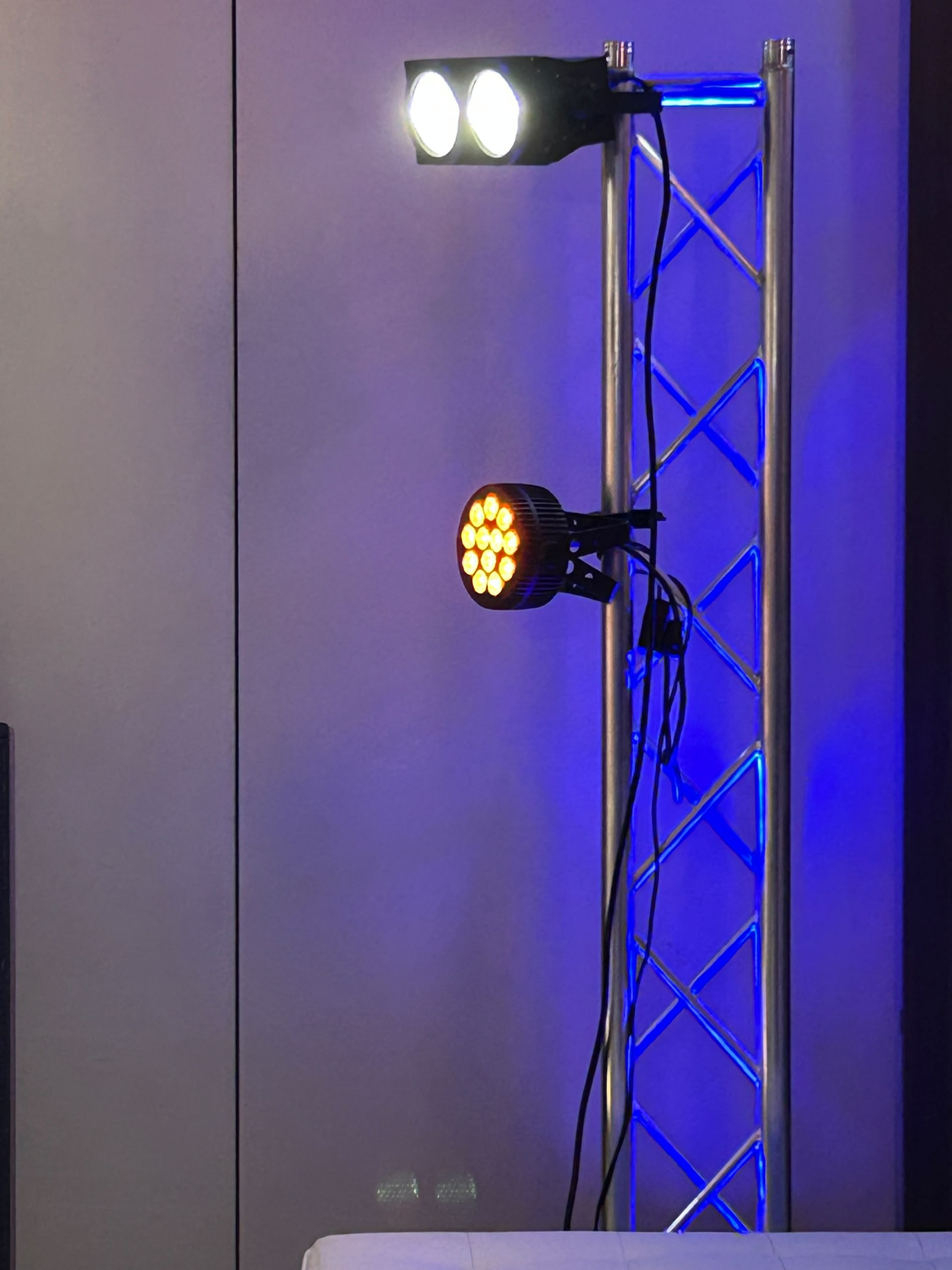 Professional stage lighting with white LED panel and yellow LED PAR lights on blue metal truss