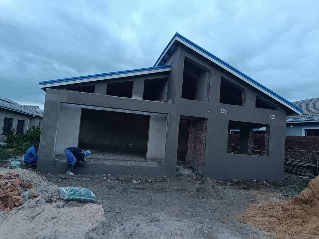 Two-storey structural building under construction, grey plastered with blue roof trim