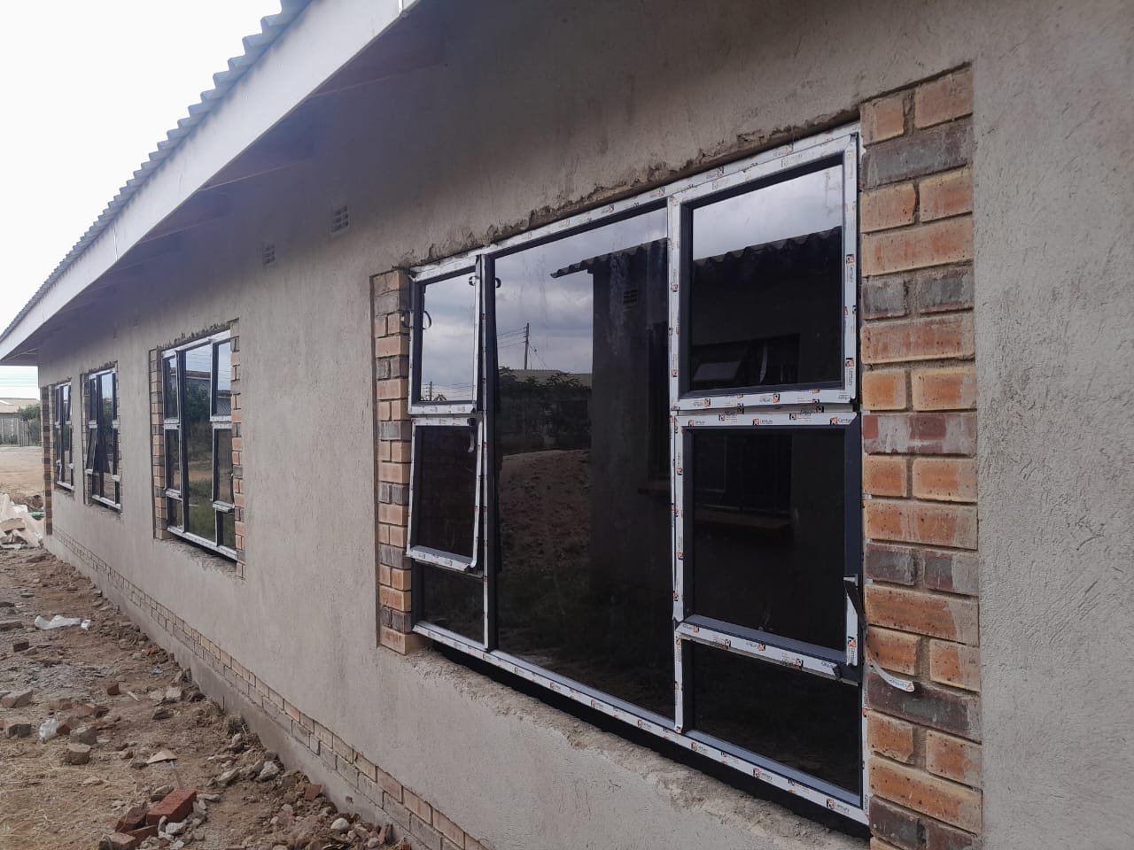 Aluminium windows — row of dark-framed tilt-and-turn windows on plastered brick wall
