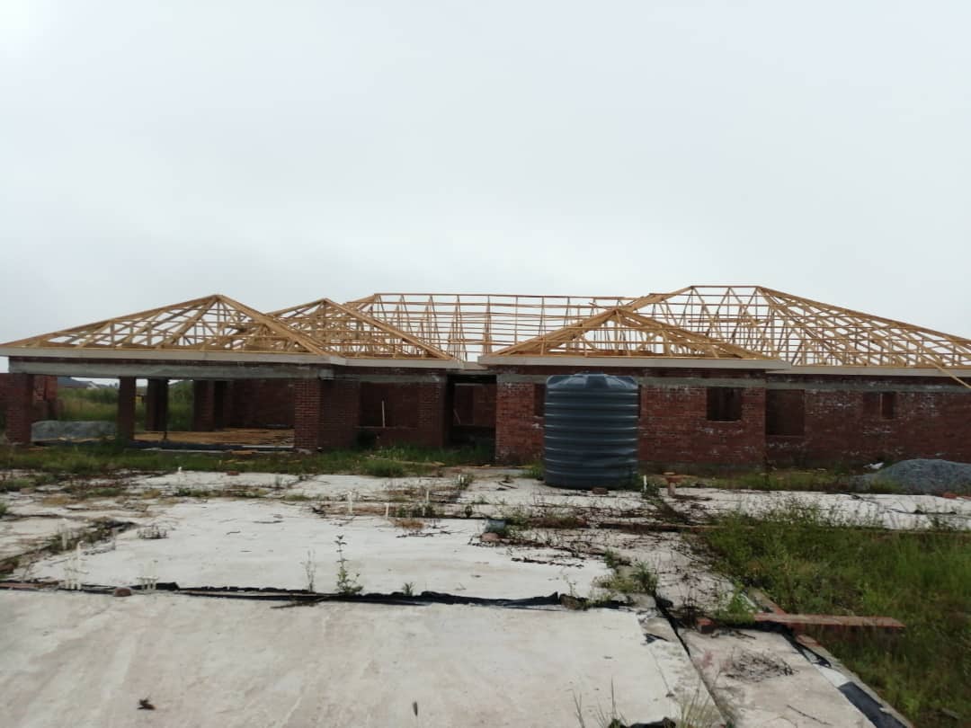 Large brick building under construction with exposed wooden roof trusses