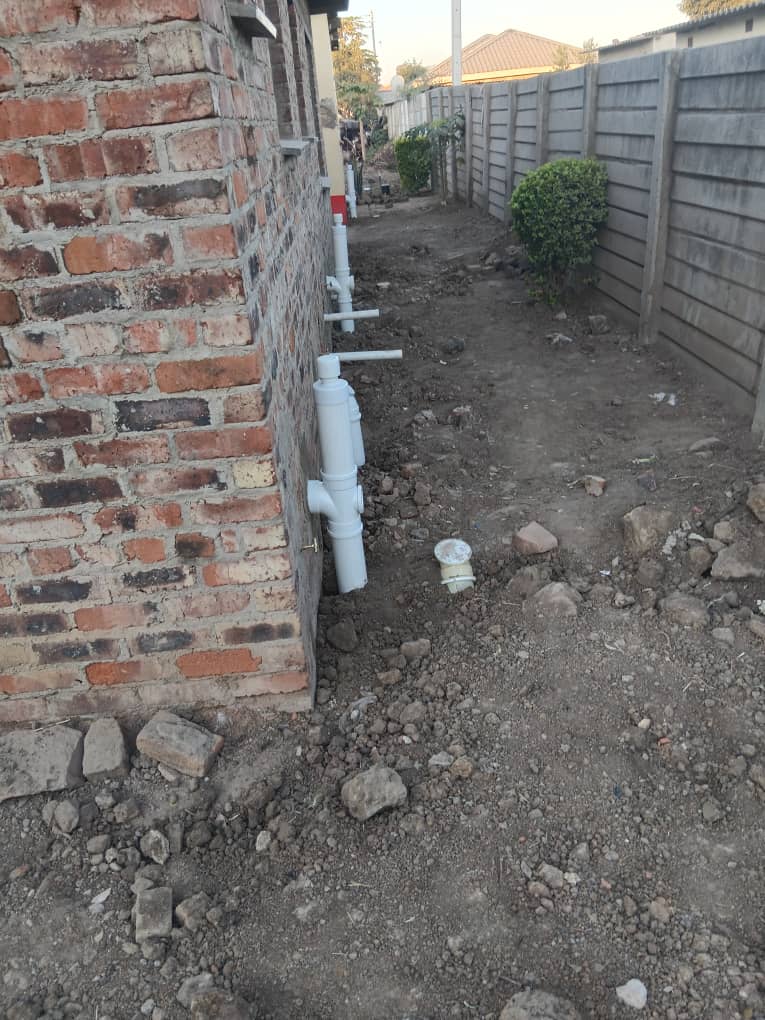 Plumbing — external PVC pipe fittings mounted on brick wall
