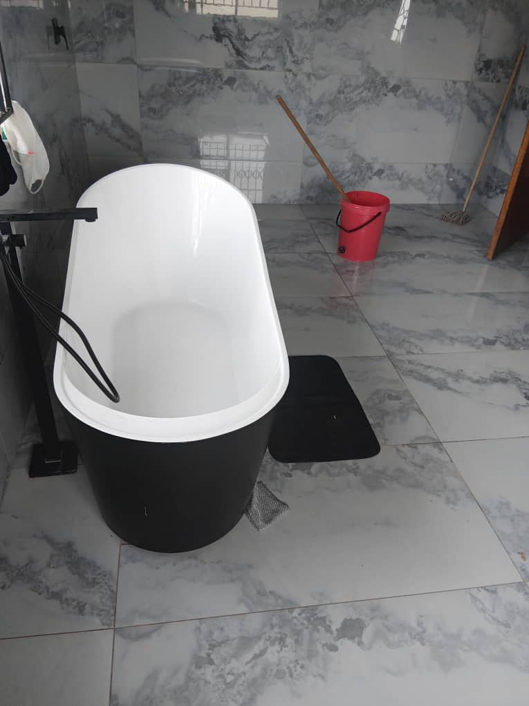 Bathroom — freestanding black and white bathtub on marble floor with marble wall tiles